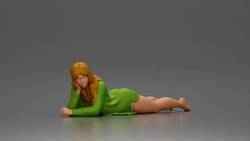 Girl with long hair in green dress lying with calm on the beach