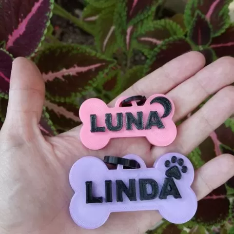 Dog tags in the shape of bones with details of canine paw prints and hearts